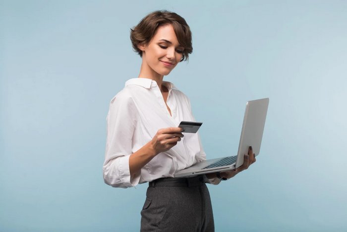 Kobieta trzymająca laptopa i kartę bankową