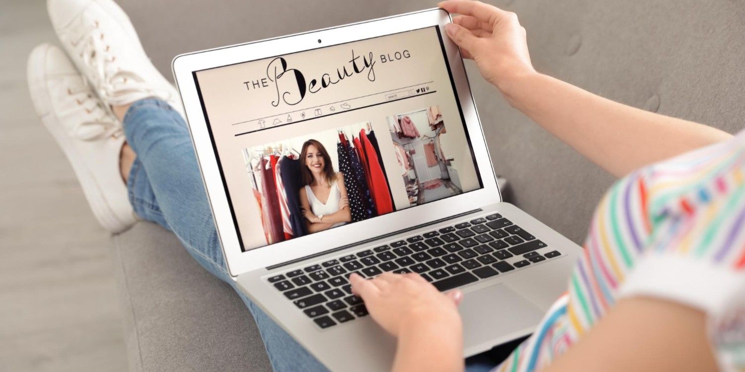 Kobieta trzymająca na kolanach laptop, na jego ekranie strona główna bloga w tematyce fashion