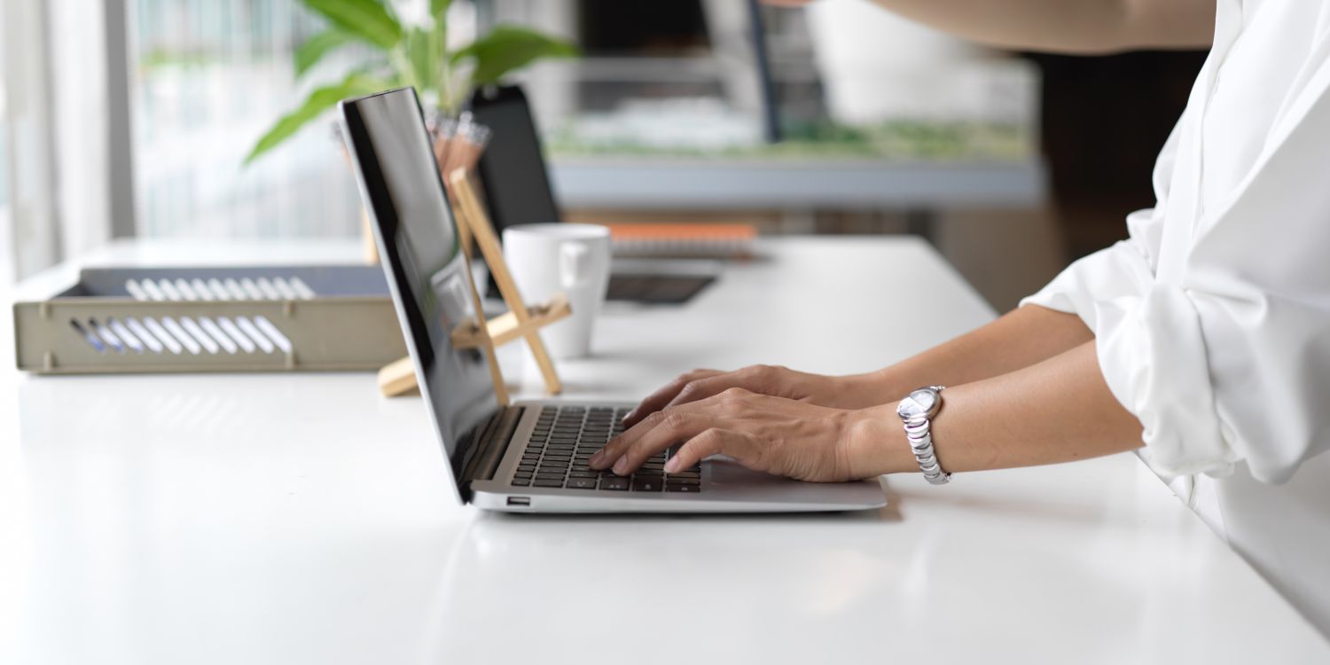 Widoczne z boku ręce osoby pracującej przy laptopie