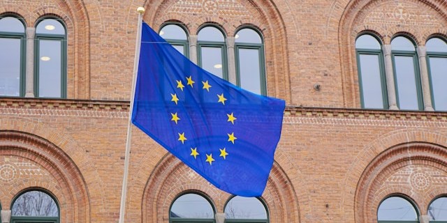 Zdjęcie z flagą Unii Europejskiej wywieszoną na ścianie z cegieł