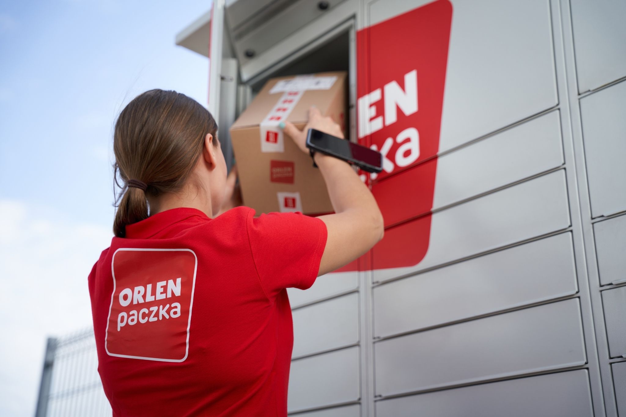 Kobieta wkładająca paczkę do paczkomatu