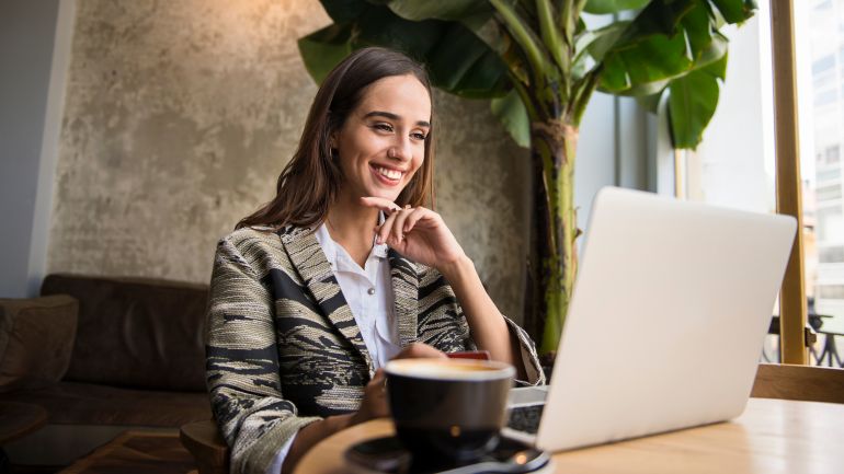 Kobieta siedząca przy stole z laptopem