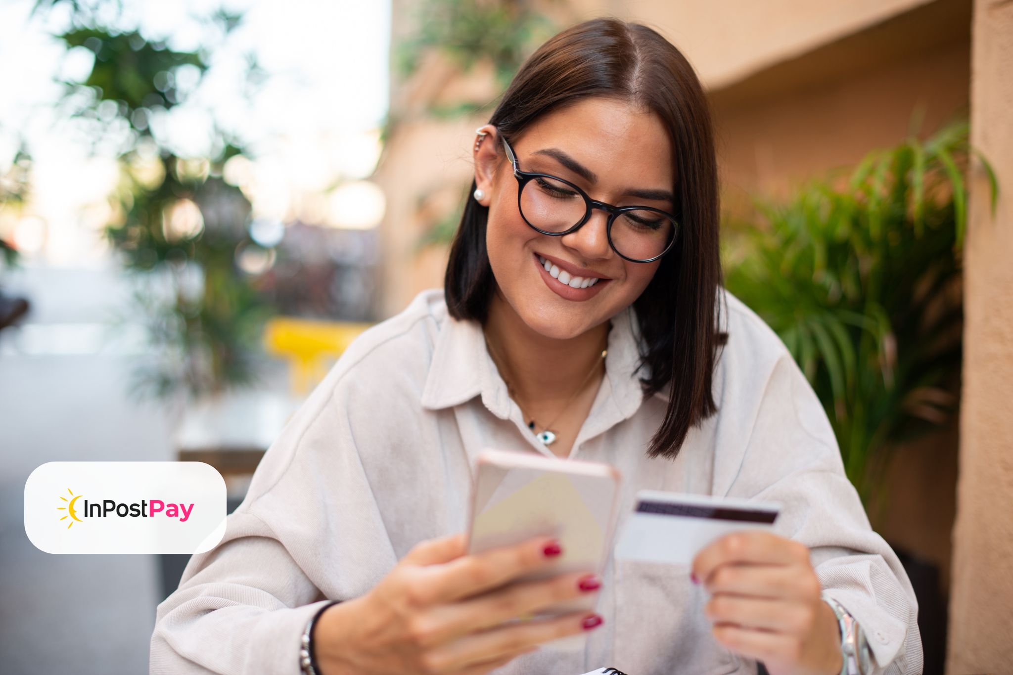 Stojąca kobieta trzymająca w ręku tablet, w tle kilka osób na spotkaniu