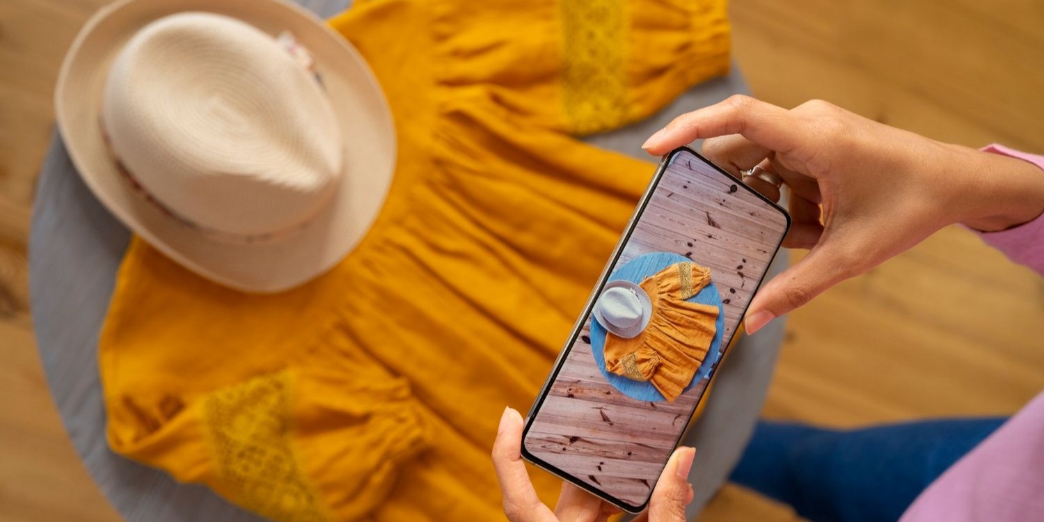 Osoba robiąca zdjęcie leżącej przed nią sukience i kapeluszowi